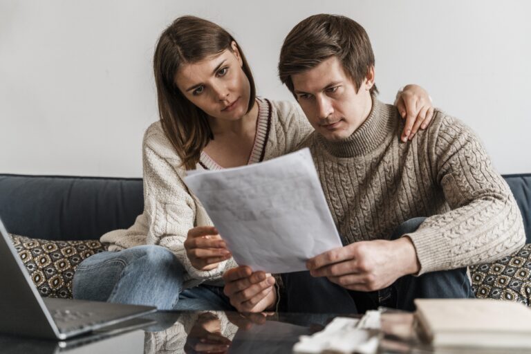 Jeune couple consultant un document pour choisir une mutuelle santé adaptée à leurs besoins.